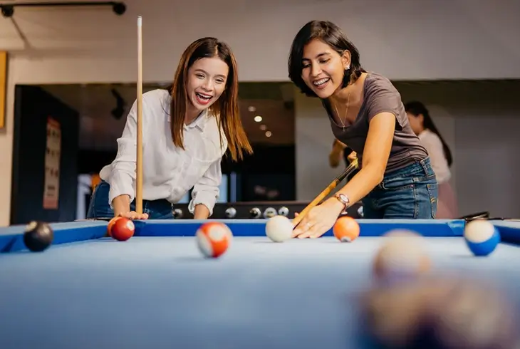 two young women playing pool